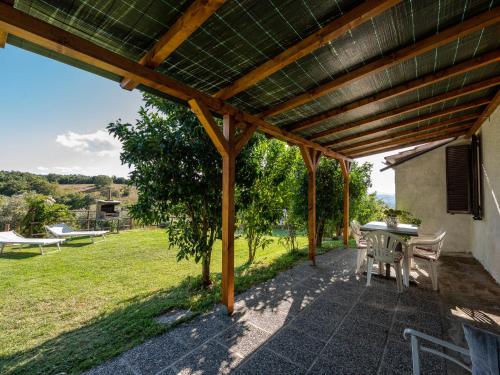 a patio with a table and chairs under a wooden pergola at Holiday Home Country House by Interhome in Montorgiali