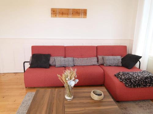 a red couch in a living room with a vase of flowers at Apartment Grand-Rue 143 by Interhome in Auberson