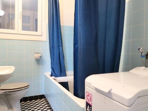 a bathroom with a blue shower curtain and a toilet at Apartment Grand-Rue 143 by Interhome in Auberson