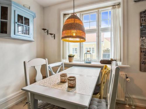 a table and chairs in a kitchen with a chandelier at Apartment Marisol - 700m from the sea in NW Jutland by Interhome in Skagen