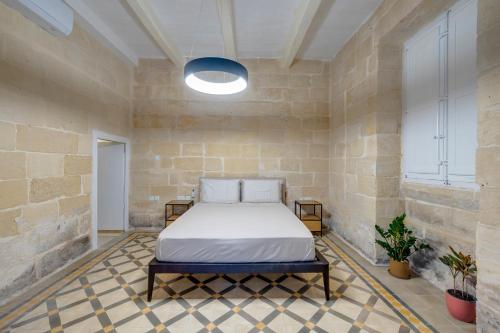 スリーマにあるSeafront Traditional Maltese Townhouse Balluta Bayのレンガの壁にベッド1台が備わるベッドルーム1室