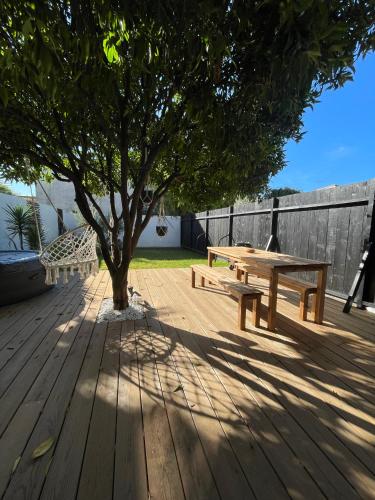 a wooden deck with a picnic table and a tree at Gites du réservoir in Mauguio