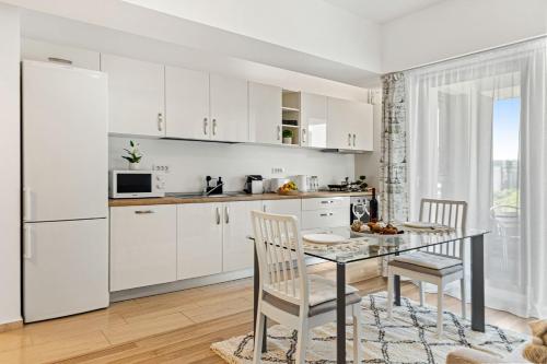 - une cuisine avec des placards blancs, une table et des chaises dans l'établissement Unirii Plaza Apartment, à Bucarest