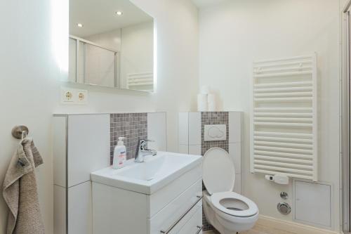 a white bathroom with a toilet and a sink at Hanseat Apartments in Hamburg