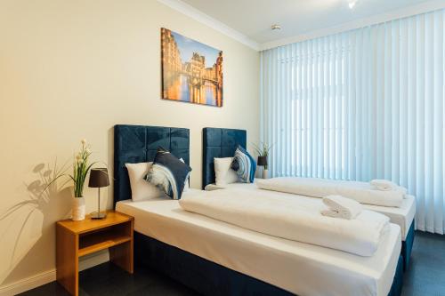 two beds in a room with white walls and windows at Hanseat Apartments in Hamburg