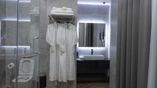 a bathroom with a sink and a shower with a robe at Five Hotel in Bishkek