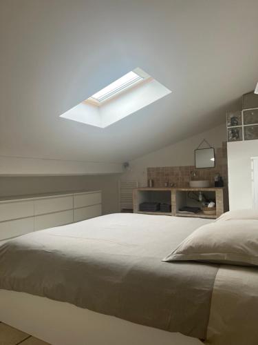 a white bedroom with a large bed with a skylight at Casa San Carlu in Grosseto-Prugna
