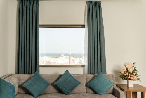 Swiss Spirit Hotel & Suites Dammam Corniche في الدمام: غرفة معيشة مع أريكة ونافذة كبيرة