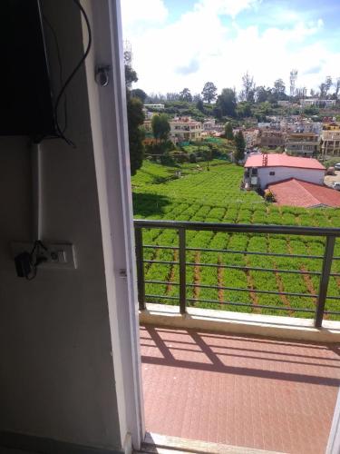 a room with a balcony with a view of a field at OOTY EVERGREEN COTTAGE in Ooty