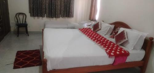 a bedroom with a white bed with red and white pillows at OOTY EVERGREEN COTTAGE in Ooty