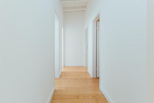 an empty corridor with white walls and a wooden floor at Hanseat Apartments in Hamburg