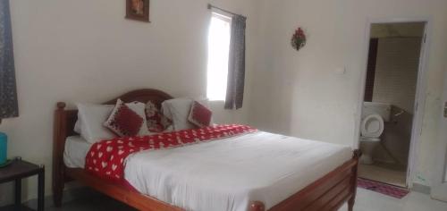 a bedroom with a bed with red and white pillows at OOTY EVERGREEN COTTAGE in Ooty