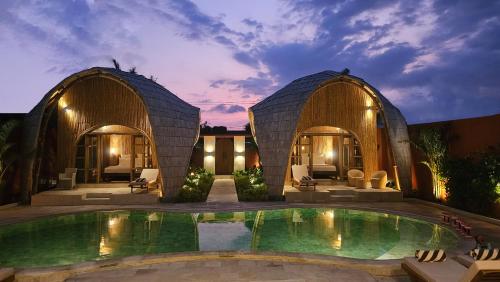 a villa with a swimming pool and two domes at Bamboo Estate Legian in Legian