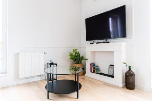 a living room with a glass table and a tv at Marina Glamour - 3pok, widok na jezioro, klimatyzacja, parking podziemny, winda, Netflix in Iława