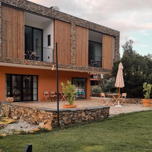 einen externen Blick auf ein Haus mit einer Terrasse und einem Sonnenschirm in der Unterkunft Quinta das Levadas - Country House & Nature in Alvoco das Várzeas