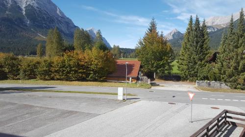 an empty parking lot with a house and mountains at Mountain Motel in Leutasch