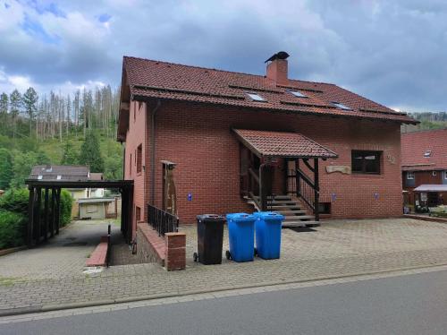 un edificio de ladrillo con tres cubos de basura delante de él en Gästehaus Harzklause 6, en Sieber