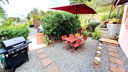 a patio with a table and a grill with a table and chairs at Le Quéléa Une case créole de charme classée 4 étoiles Y être c'est y être bien in LʼEntre-Deux
