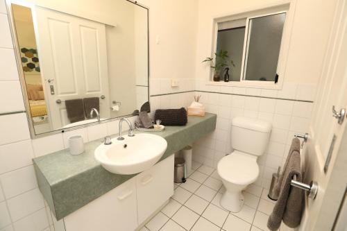 uma casa de banho com um lavatório, um WC e um espelho. em 1 Bed Apartment Close to the Beach and Town em Port Douglas