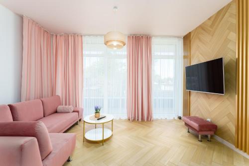 salon z różową kanapą i telewizorem w obiekcie Apartament Pudrowy Ku Morzu by HolidaySun w Sianożętach