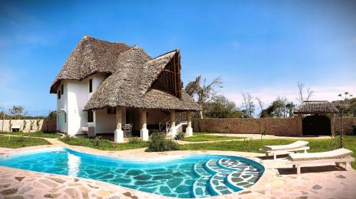 uma casa com telhado de palha e uma piscina em Nyuso za Afrika em Watamu