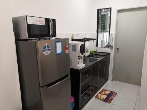 a kitchen with a refrigerator and a tv on top of it at Hamin De Thor Homestay-Benoni Garden Apartment in Papar