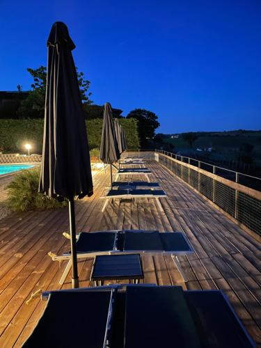 una fila di ombrelloni e sedie a sdraio su una terrazza di Azienda Agricola Tenuta del Barone a Calliano