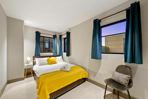 - une chambre avec un lit doté d'une couverture jaune et d'une fenêtre dans l'établissement 2 Bed Lux Apartments near Central London FREE WIFI by City Stay Aparts London, à Londres