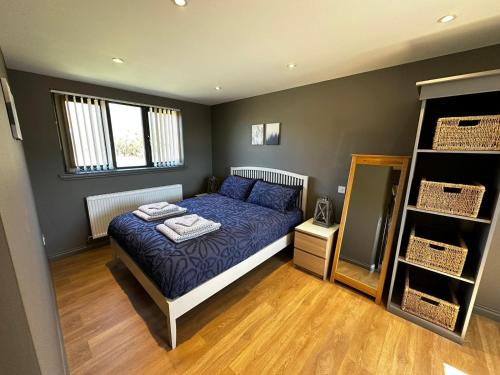 um quarto com uma cama com um edredão azul em Countryside Chalet near Glasgow em Glasgow