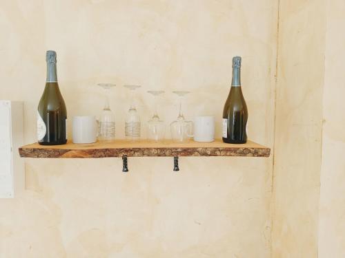 a shelf with wine bottles and glasses on it at Bulles de Lune in Sacy