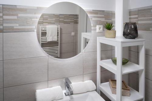 La salle de bains est pourvue d'un lavabo blanc et d'un miroir. dans l'établissement Jacuzzi- Chambre Secrète- Love Room- Une Pause à Deux, à Château-Landon