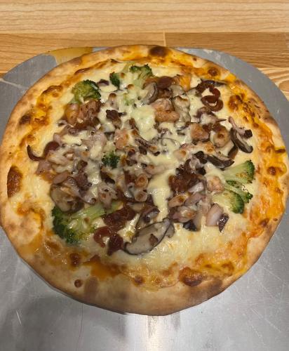 a pizza with mushrooms and broccoli on a table at Uyen's House in Con Dao