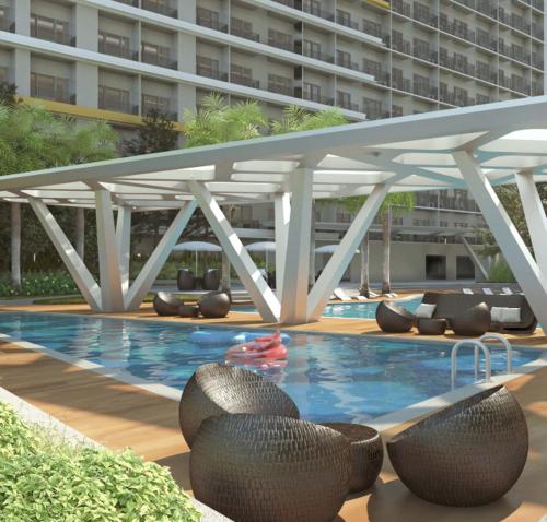 una piscina con sillas y un gran edificio en Fame Stays, en Manila