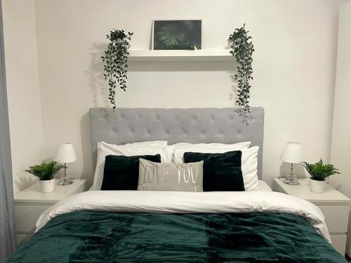 a bedroom with a bed with a green comforter and plants at Stockwood Apartment by Cliftonvalley Apartments in Bristol