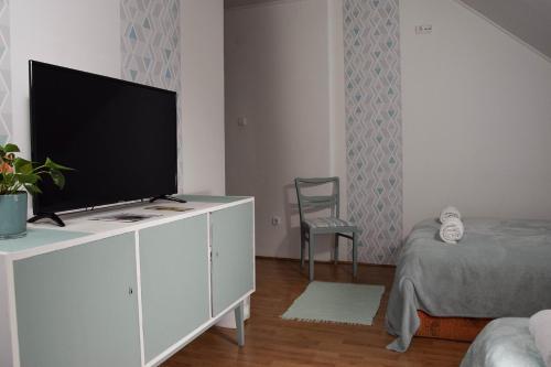 a living room with a flat screen tv on a white cabinet at Kiskut Liget Pension in Győr