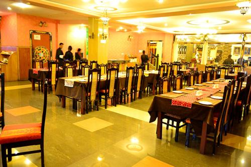 a dining room with tables and chairs with people in the background at Hotel Migmar in Thimphu