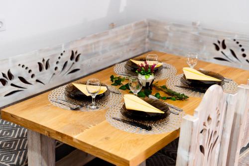 a wooden table with plates and wine glasses on it at Kata Kulcsosház in Odorheiu Secuiesc