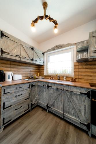 a kitchen with wooden cabinets and a window at Kata Kulcsosház in Odorheiu Secuiesc