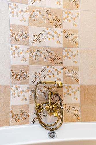 a bath tub with a gold shower head on a wall at Kata Kulcsosház in Odorheiu Secuiesc
