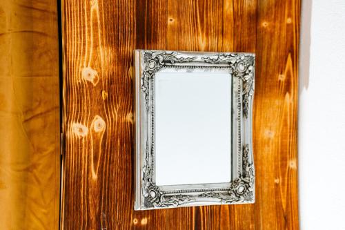a mirror in a silver frame on a wooden wall at Kata Kulcsosház in Odorheiu Secuiesc