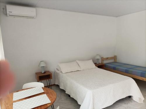 Dormitorio blanco con cama y mesa en La Residenza, en Santa Ana