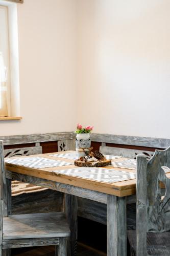a wooden table with two chairs and a vase on it at Kata Kulcsosház in Odorheiu Secuiesc