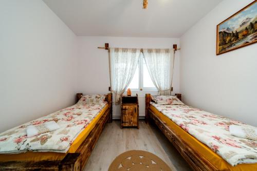 two beds in a room with a window at Kata Kulcsosház in Odorheiu Secuiesc
