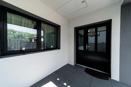 a room with a black door and two windows at Kata Kulcsosház in Odorheiu Secuiesc