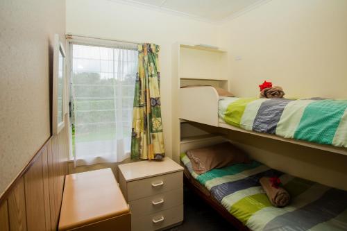 a small bedroom with two bunk beds and a window at Kiwi Classic in Matapouri