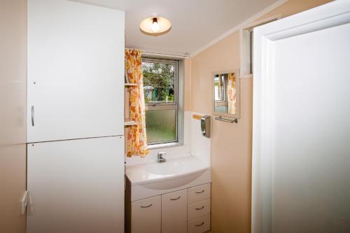 a bathroom with a sink and a white refrigerator at Kiwi Classic in Matapouri