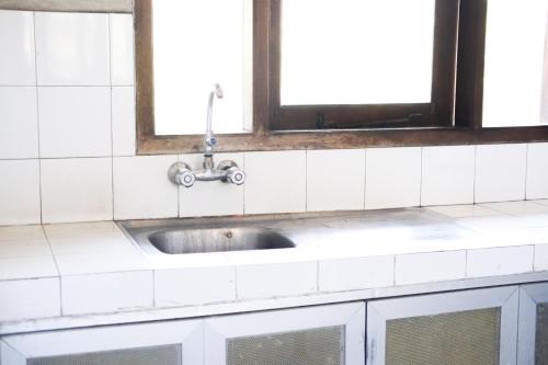 a sink in a white tiled kitchen with a window at 3BR AC Rumah Liburan Pasteur Bandung in Bandung