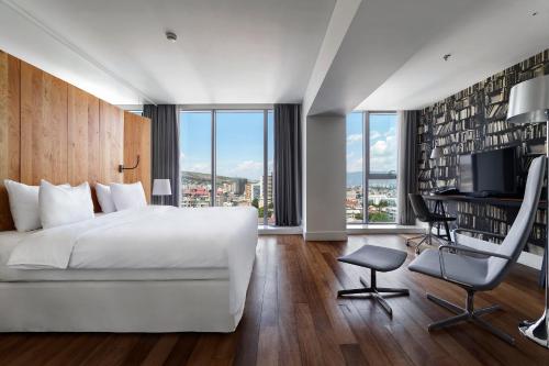 a bedroom with a white bed and a desk and chair at Holiday Inn - Tbilisi, an IHG Hotel in Tbilisi City