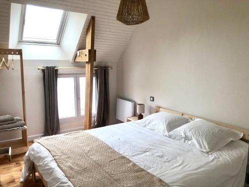 une chambre avec un lit avec des draps blancs et une fenêtre dans l'établissement Gite du Verger de Kerduel, à Moëlan-sur-Mer