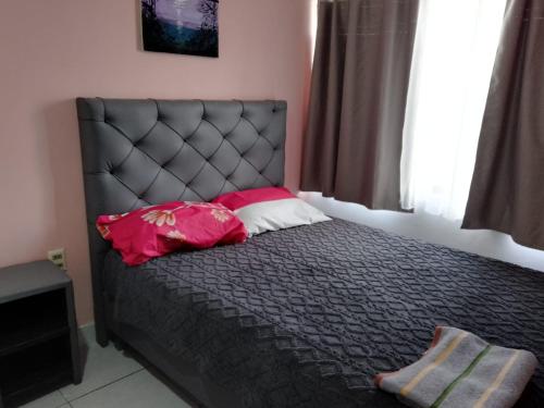 a bedroom with a black bed with pink pillows at departamento familiar, Tarija te espera!! in Tarija